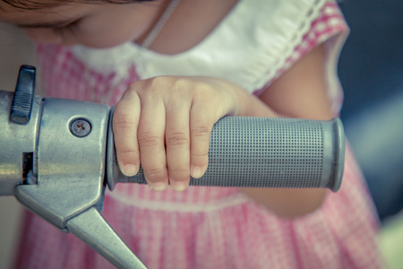 kid hand holding motorcycle handle bar in vintage color toneの写真素材