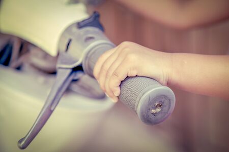 kid hand holding motorcycle handle bar in vintage color toneの写真素材