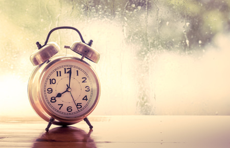 retro alarm clock on wooden table on rainy day window background in vintage color tone retro alarm clock on wooden table on rainy day window background in vintage color tone