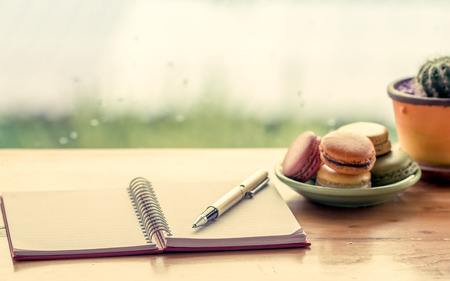 Pen on notebook decorate with macaroon on  rainy day window background  in vintage color toneの写真素材