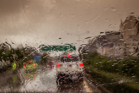 blurred image of traffic view through a car windscreen covered in rain