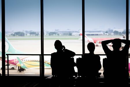 Silhouettes of businessman and passengers traveling on airport, waiting at the plane boarding gates.の写真素材