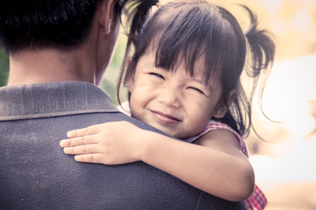 Father and child,happy little girl resting on her father's shoulder in the park, vintage filter effectの写真素材