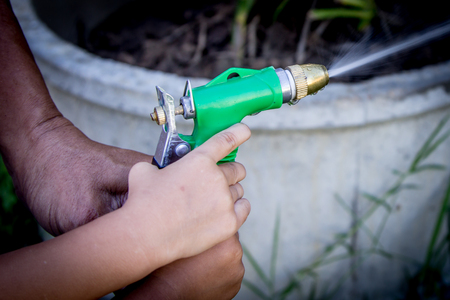 Father and child hand help watering plant in garden,selective focusの写真素材