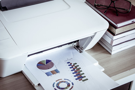 Printer with eyeglasses on books on wooden table,vintage filterの写真素材