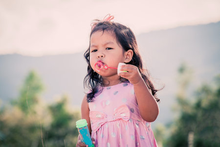 Child cute little girl blowing a soap bubbles in the park,vintage filter