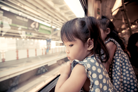 Child little girl looks in train window in vintage color filterの写真素材