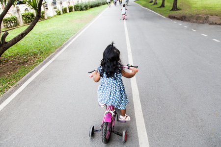 Child cute little girl riding bike in park