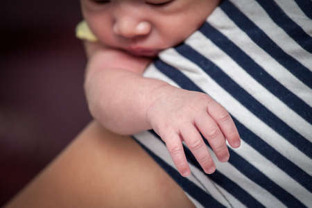 focus on newborn baby boy hand on his mother shoulderの写真素材