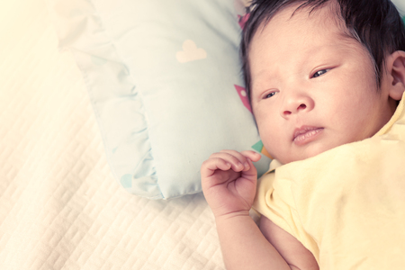 Cute newborn baby boy is lying on his bed  in vintage color filterの写真素材