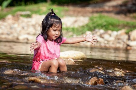 Child little girl having fun to play in waterfall  in summer timeの写真素材