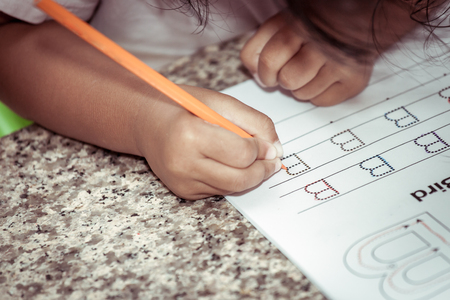 Child hand writing her homework with crayon,vintage color filterの写真素材