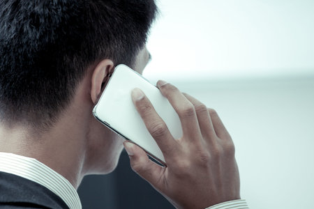 Businessman is speaking on the phone in office in blue color tone