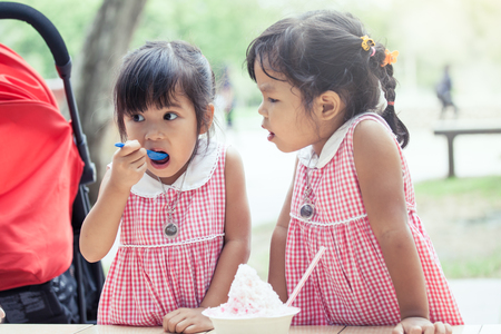 two little girls eat ice cream together in vintage color toneの写真素材