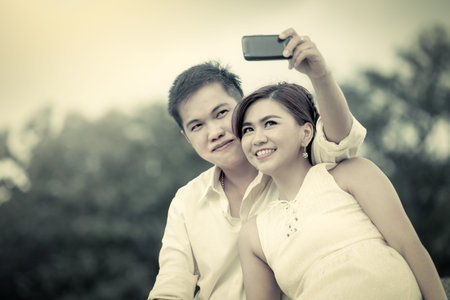 Young couple in love taking a selfie in the park in vintage color tone