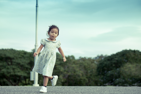 Child little girl running in the park in vintage color toneの写真素材