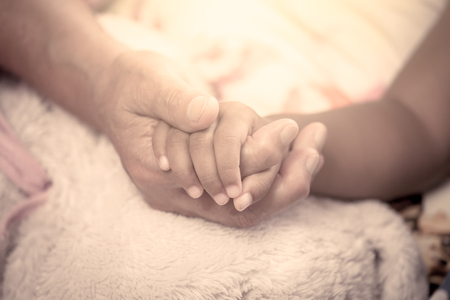 elder and kid holding hand together in vintage color toneの写真素材