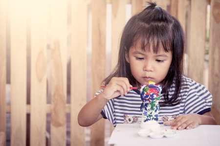 Child painting,cute little girl having fun to paint on stucco doll together in vintage color toneの写真素材