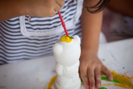 Child painting, little girl having fun to paint on stucco dollの写真素材