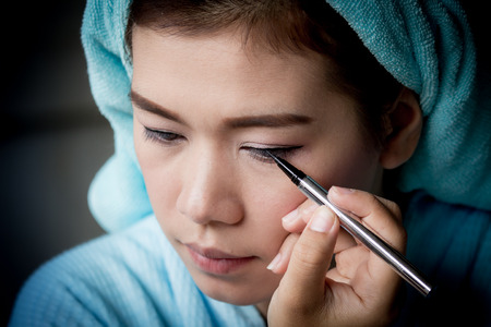 Makeup concept, Closeup asian woman applying eyeliner on eyeの写真素材