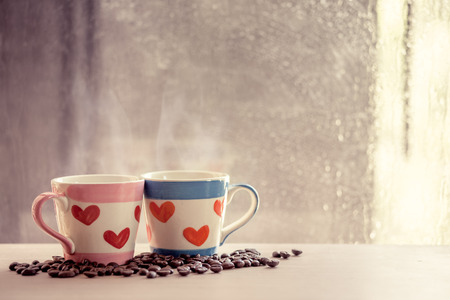 two lovely glass with coffee bean on rainy day window background  in vintage color toneの写真素材