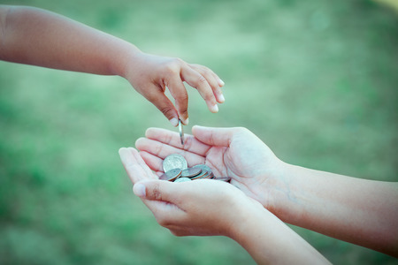 child little girl giving coin to mother as saving money concept in vintage color toneの写真素材