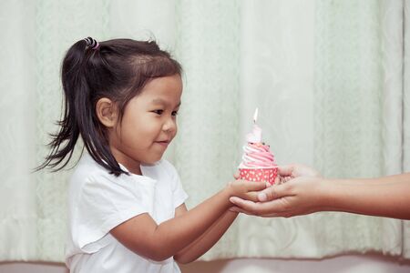 asian little girl having fun to blowing birthday cupcake in vintage color toneの写真素材