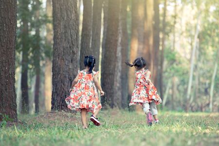 two little girls running and having fun in the park in vintage color toneの写真素材