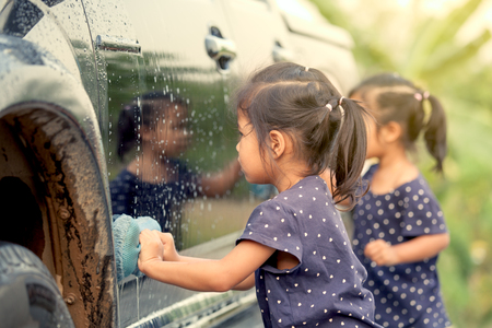 Cute asian little girl washing car in vintage color toneの写真素材