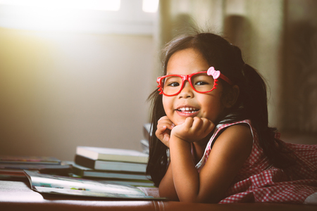Cute asian little put on eyeglasses reading a book in vintage color toneの写真素材