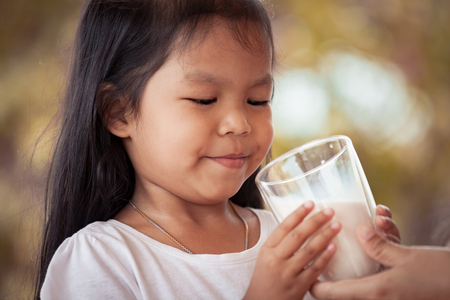 Asian little girl try to drink a milk from glass she don't like itの写真素材