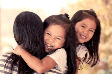 happy asian little girls hugging mother and having fun to play with mother in vintage color toneの写真素材