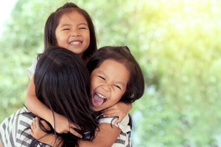 happy asian little girls hugging mother and having fun to play with mother in vintage color toneの写真素材