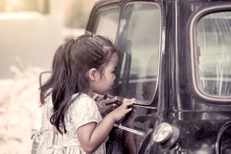 Cute asian little girl looking through car mirror for looking something in the car in vintage color toneの写真素材