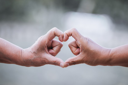 Two older women making heart shape with hands together in vintage color toneの写真素材