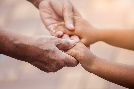 Grandmother and child little girl holding hand together with love in vintage color toneの写真素材