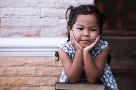 Asian little girl rest her chin on her hands in outside in vintage color toneの写真素材