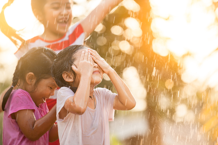 Asian children having fun to play with the rain together in the park in vintage color toneの写真素材