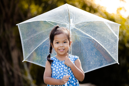 Portrait of cute asian little girl with umbrella in rain in vintage color toneの写真素材
