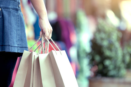 Woman hand holding shopping bags on the street in the shopping mall in vintage color tone