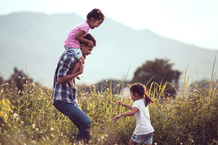 Father and daughter having fun and playing together in the cornfield and child riding on father's shoulders in vintage color toneの写真素材