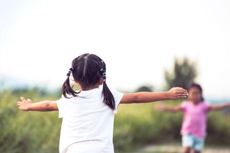 Back view of asian little girl raise her hand and waiting her sister to hug each other in vintage color toneの写真素材