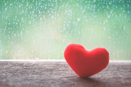 Red heart on rainy day window background in vintage color toneの写真素材