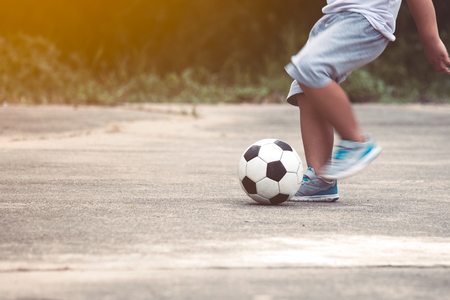 Little boy playing football in the countryside in vintage color toneの写真素材