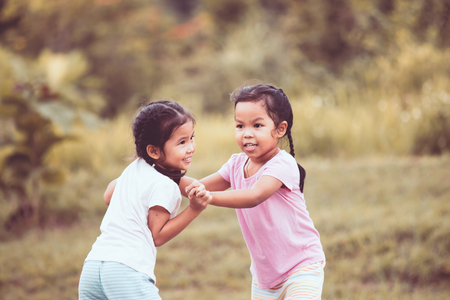 Two asian little girls playing together in the park in vintage color toneの写真素材