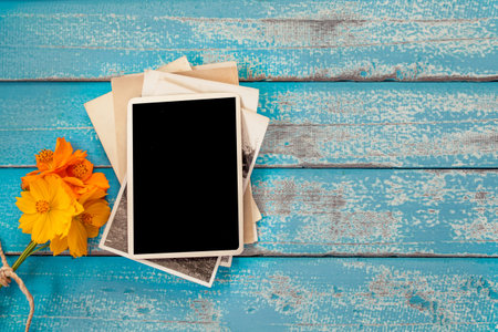 Blank photo frame album with flower on old blue wood background