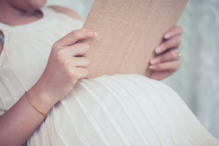 Pregnant woman reading a book prepare for birth and babyの写真素材