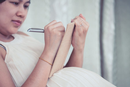 Pregnant woman writing in notebook to list necessary things prepare for birth and babyの写真素材