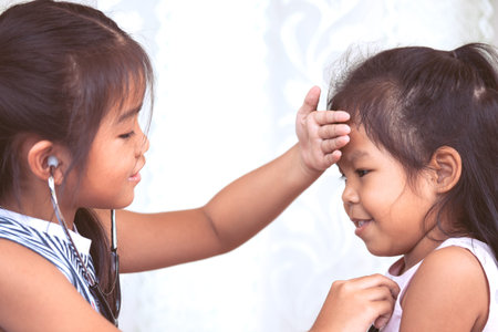 Two cute asian little child girls playing doctor and patient together in vintage color toneの写真素材