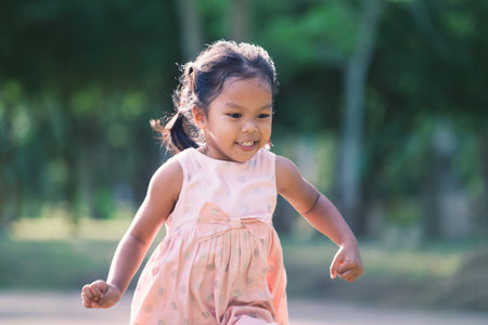 Cute asian child girl running in the park in vintage color toneの写真素材